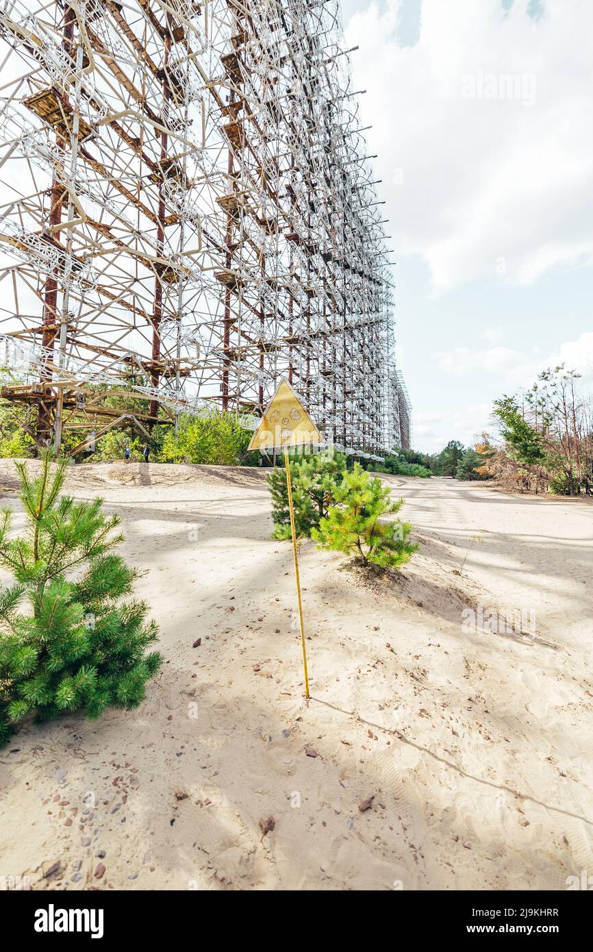 Dangerous Radiation Sign Post in front of the Duga Radar in Pripyat Chernobyl Exclusion Zone on a summer day Stock Photo