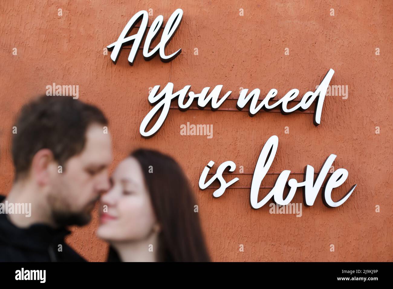 Young happy couple in love, focus on background. All you need is love message. Stock Photo