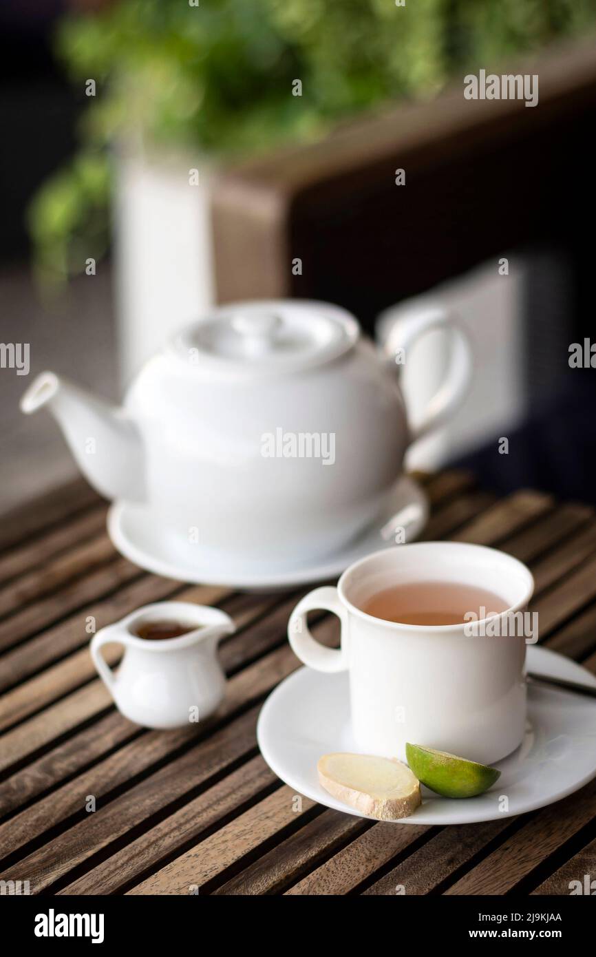 organic ginger tea pot and cup set on wooden cafe table outdoors Stock Photo