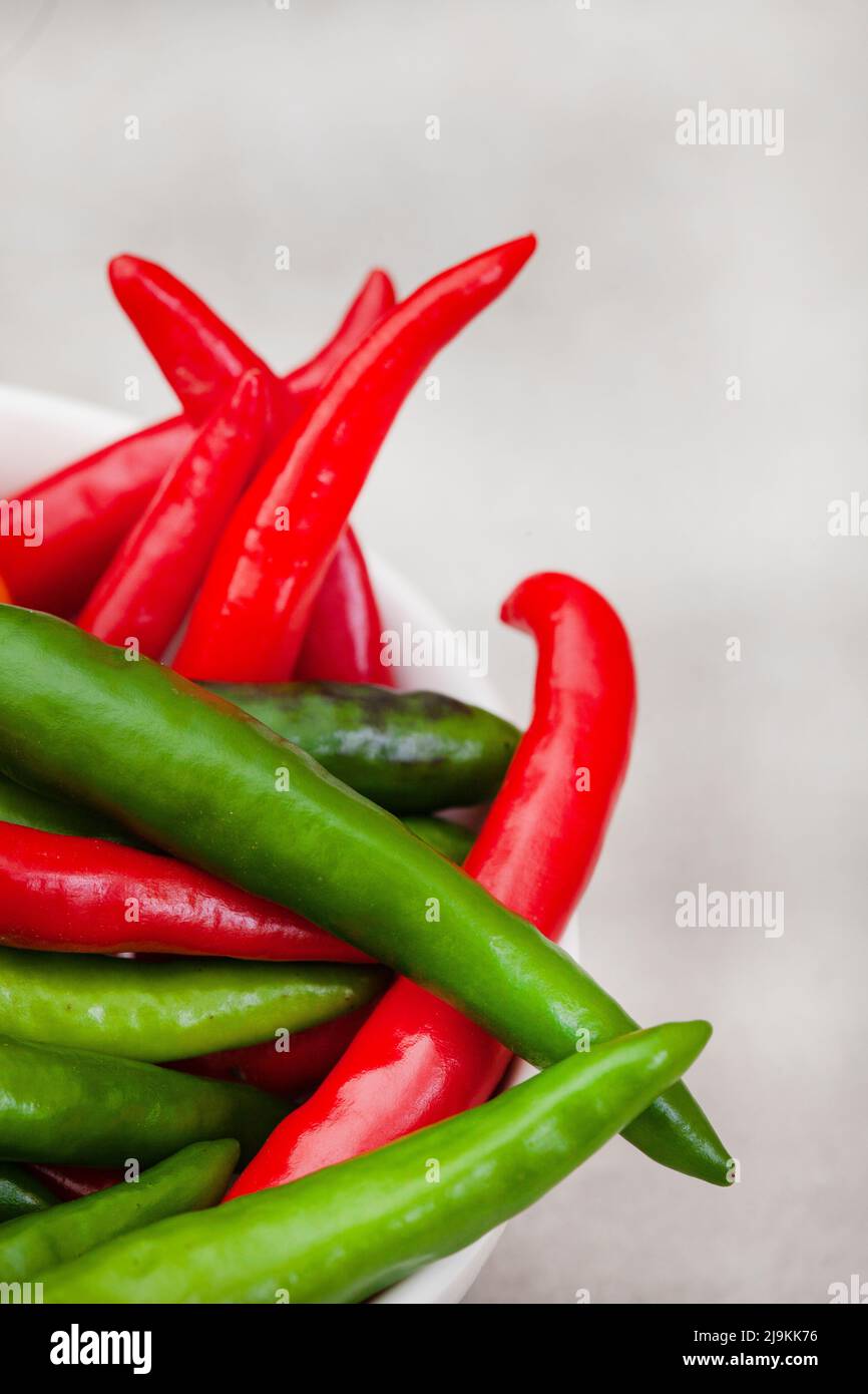bright small red and green chilies on light grey with copy space Stock Photo