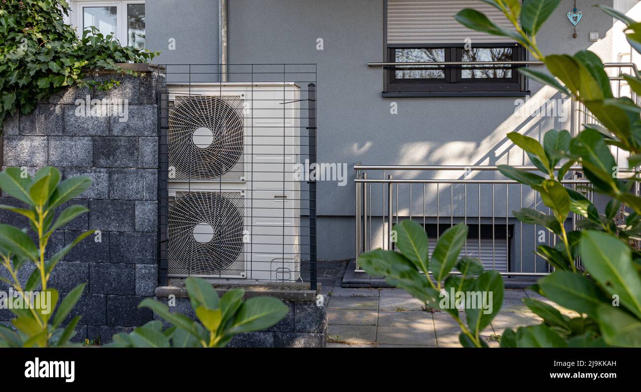 Air source heat pumps installed on the garden front of a modern house. Renewable energy concept Stock Photo
