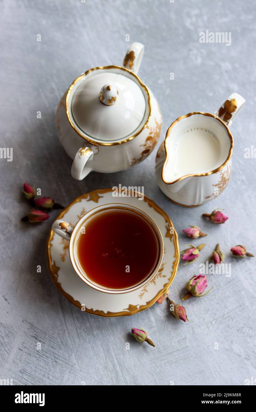 Tea with roses close up photo. Herbal tea in a small white ceramic cup on a table. Light grey background with copy space. Stock Photo