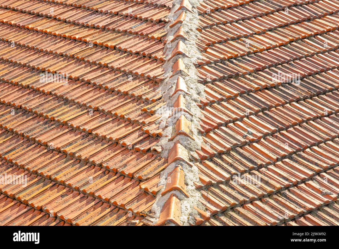 Weathered roof tile in orange color with corner of the roof, old and dirty tiles, wide angle Stock Photo