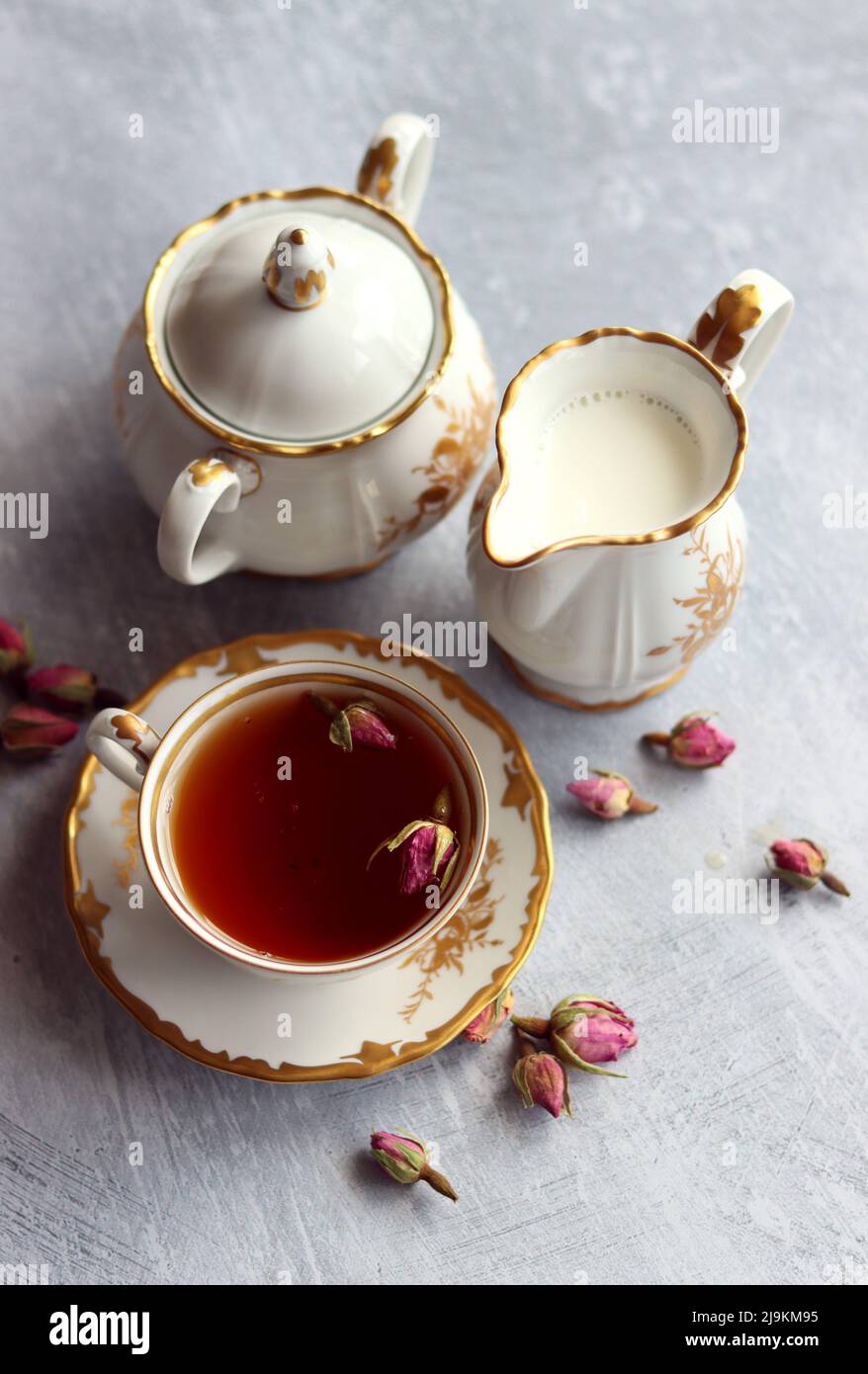 Tea with roses close up photo. Herbal tea in a small white ceramic cup on a table. Light grey background with copy space. Stock Photo