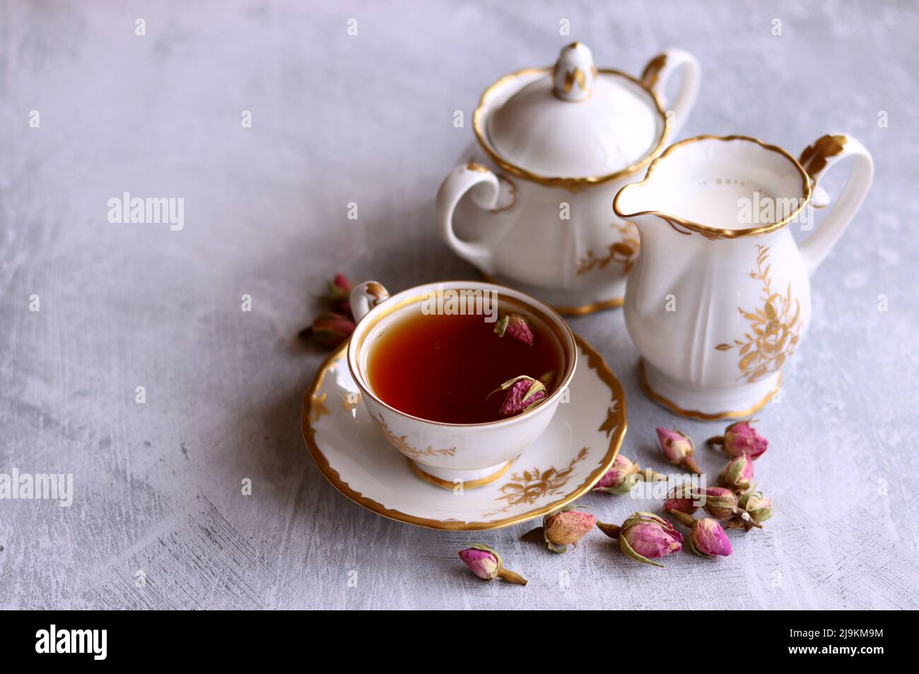 Tea with roses close up photo. Herbal tea in a small white ceramic cup on a table. Light grey background with copy space. Stock Photo