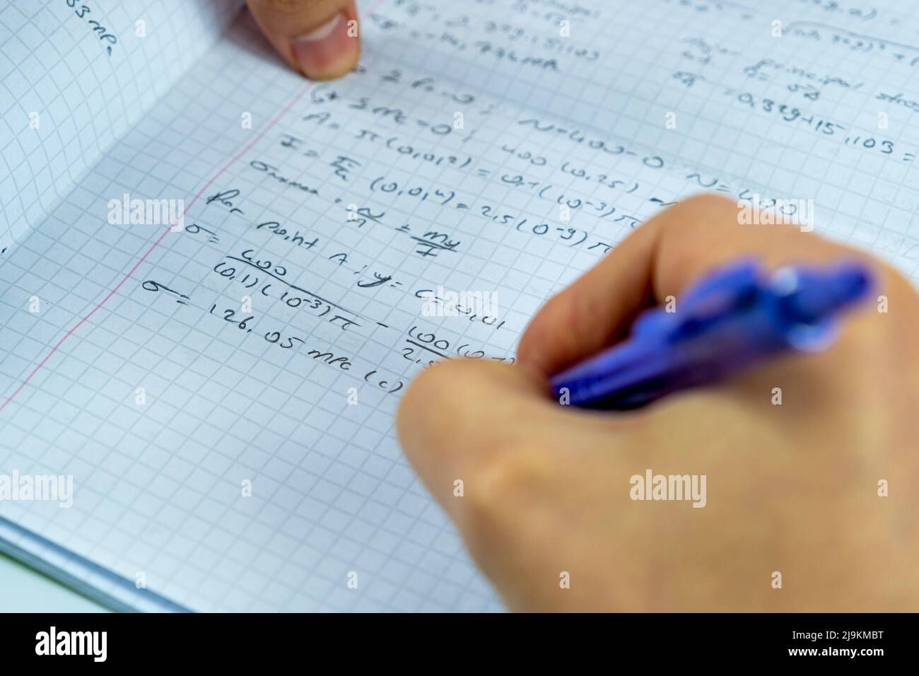 Mathematical numbers on a notebook and man hand holding purple pencil, focus on solution idea, studying math concept, sitting view Stock Photo