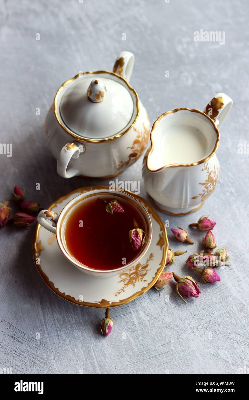 Tea with roses close up photo. Herbal tea in a small white ceramic cup on a table. Light grey background with copy space. Stock Photo