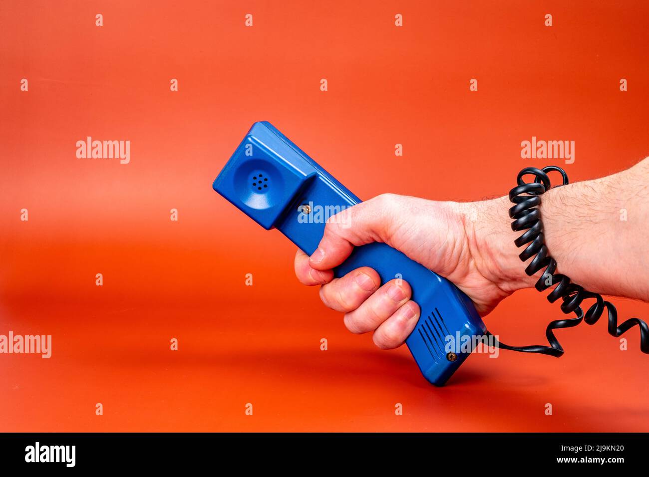 Hand holding a blue phone, with the phone cord wrapped around the arm
