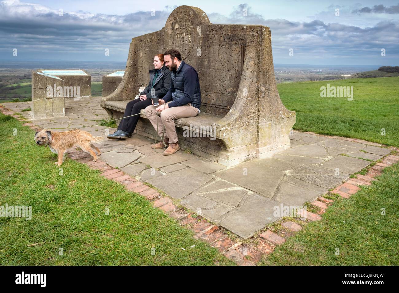A couple take in the views from the Devil's Dyke Commemorative Seat on the South Downs near Brighton. Stock Photo
