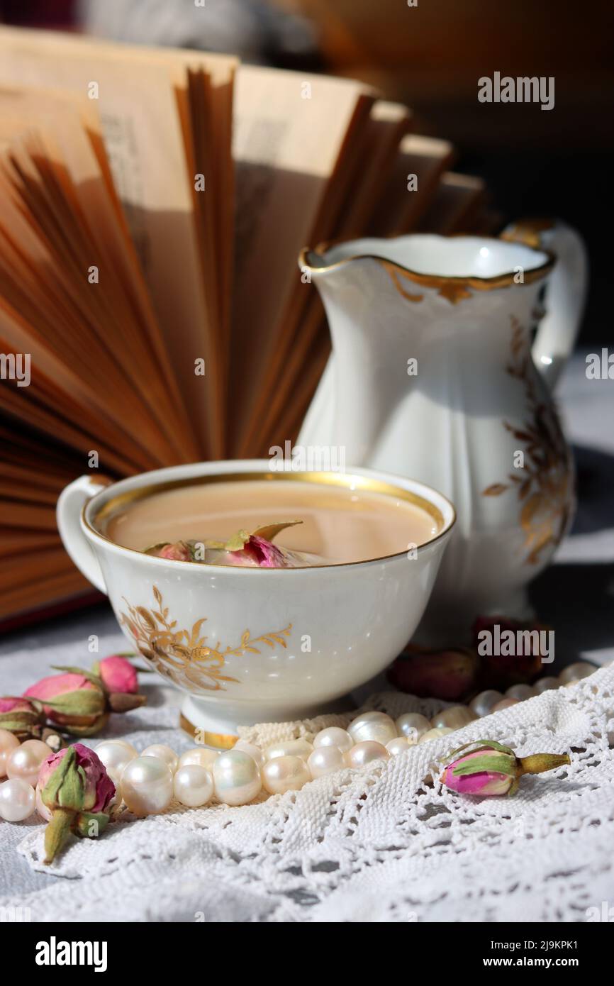 Tea with roses close up photo. Herbal tea in a small white ceramic cup on a table. Light grey background with copy space. Stock Photo