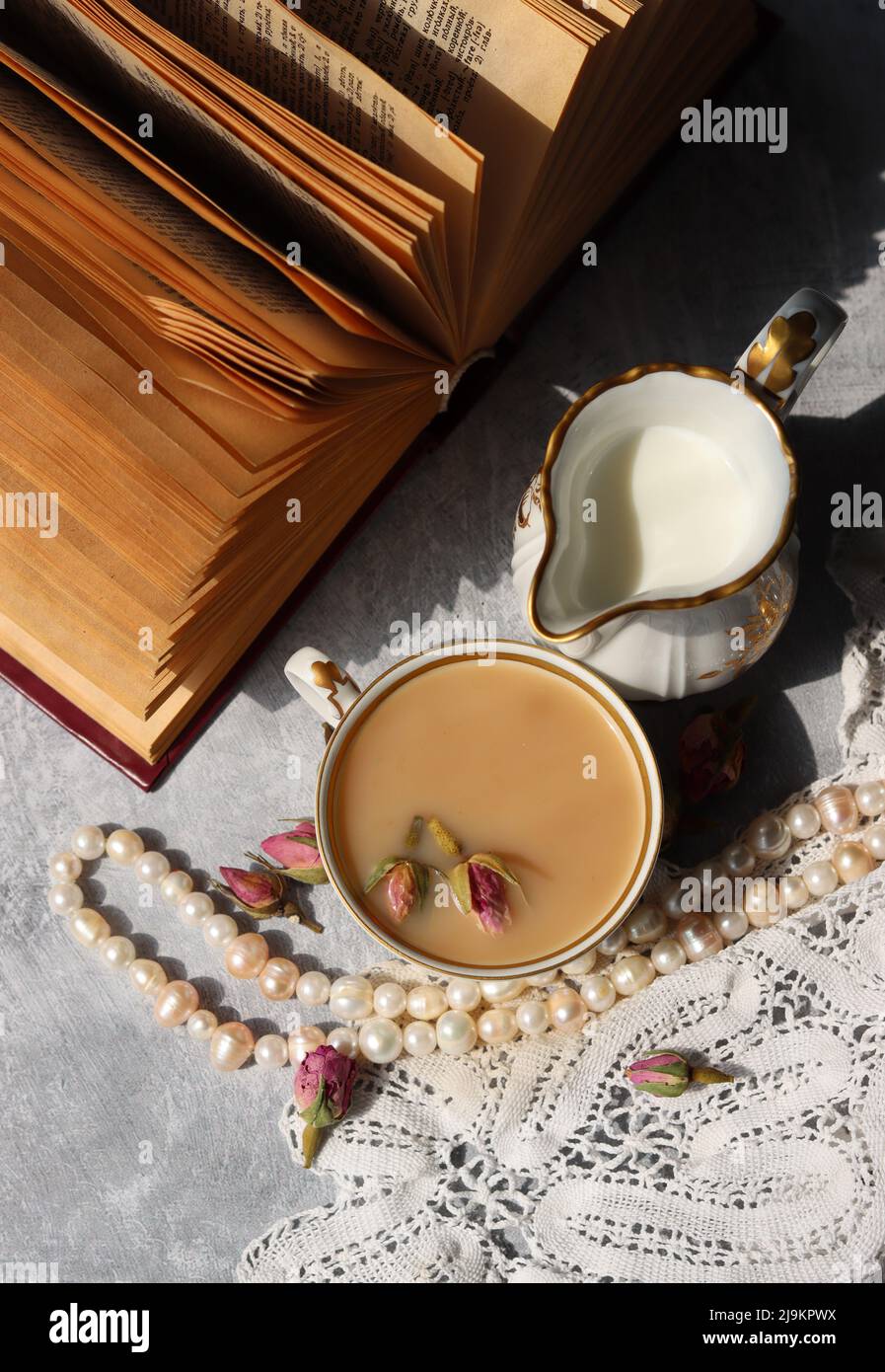 Tea with roses close up photo. Herbal tea in a small white ceramic cup on a table. Light grey background with copy space. Stock Photo