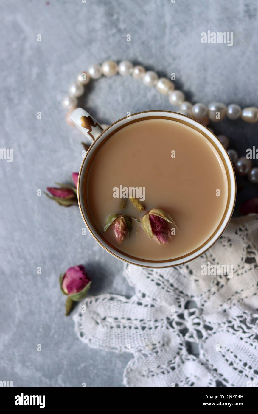 Tea with roses close up photo. Herbal tea in a small white ceramic cup on a table. Light grey background with copy space. Stock Photo