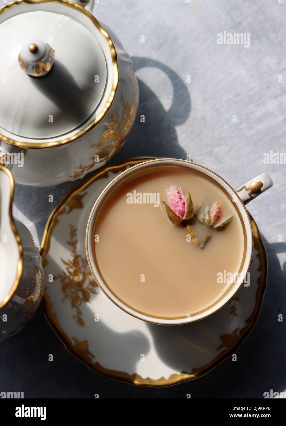 Tea with roses close up photo. Herbal tea in a small white ceramic cup on a table. Light grey background with copy space. Stock Photo