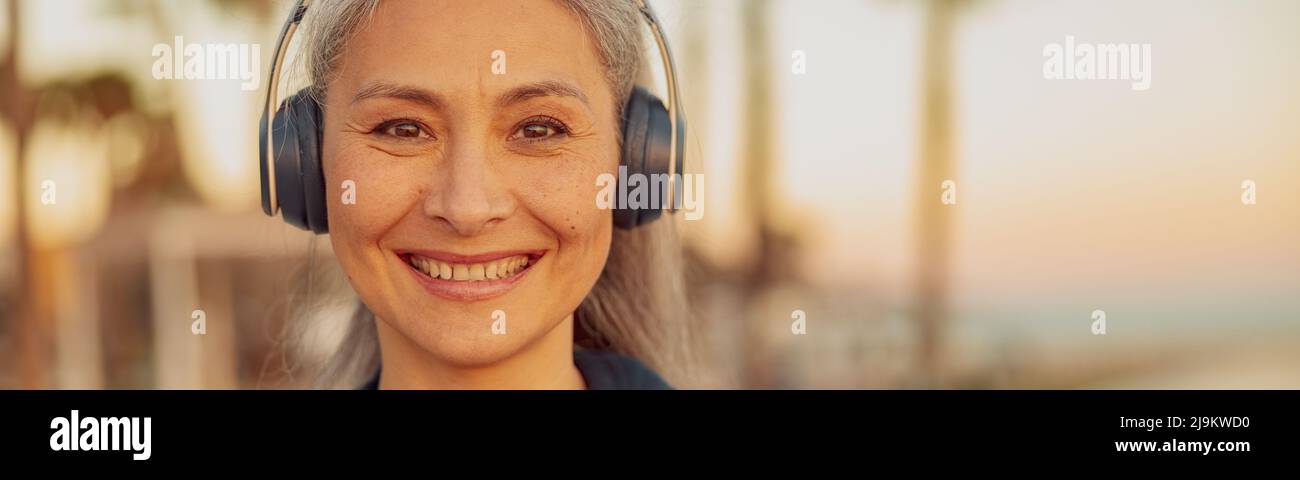 Portrait of happy woman listening to music on headphones on the beach Stock Photo