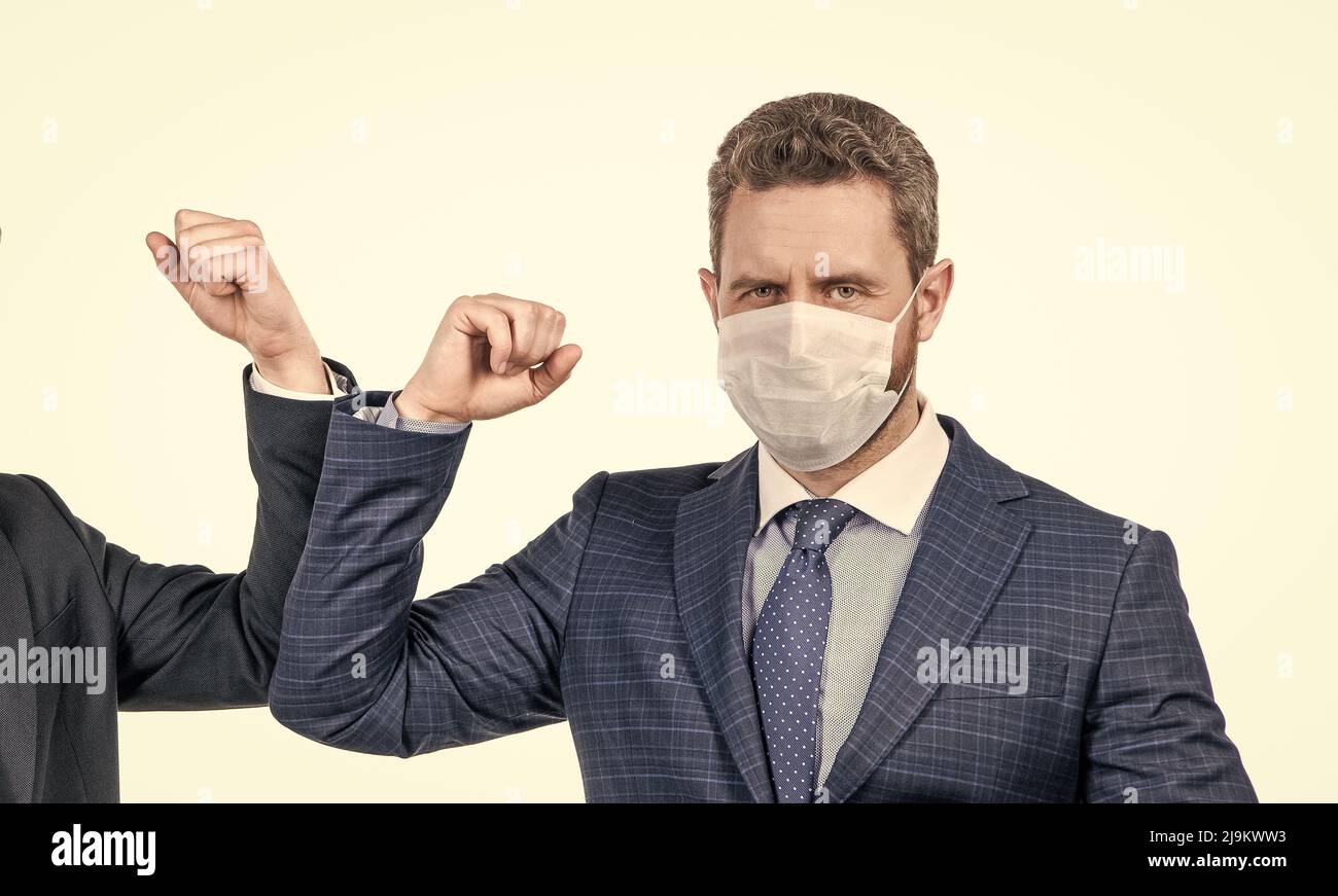 Man broker in face mask touch elbows with colleague using coronavirus greeting, elbow bump Stock Photo
