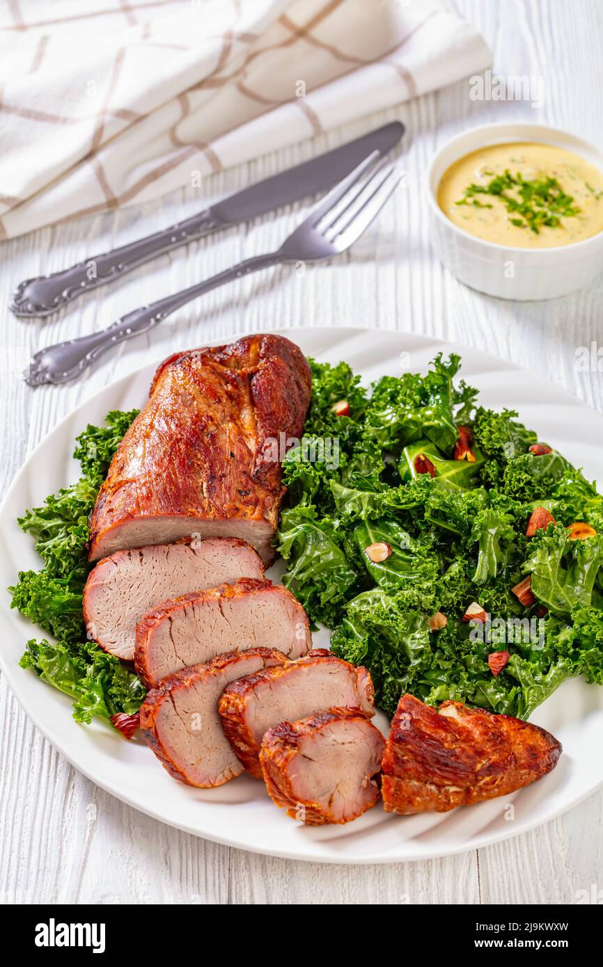 Roast Pork Tenderloin with Creamy Mustard Tarragon Sauce on white plate with fresh kale and