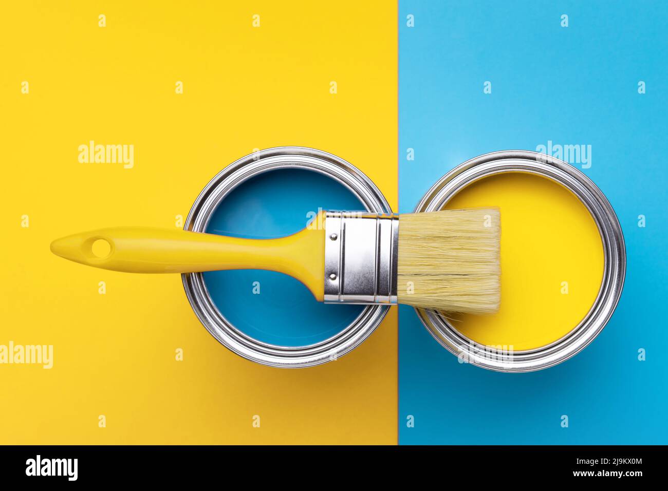Can of yellow paint with brush on yellow and blue background. Top view, repair concept. Stock Photo