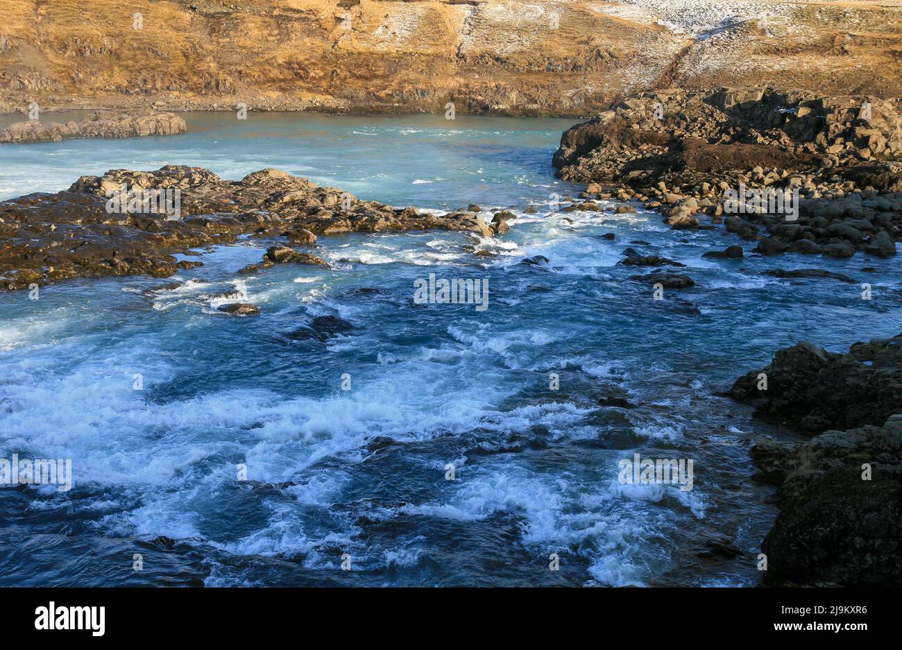 Cold river powerfully flowing between rocks in Icelandic landscape