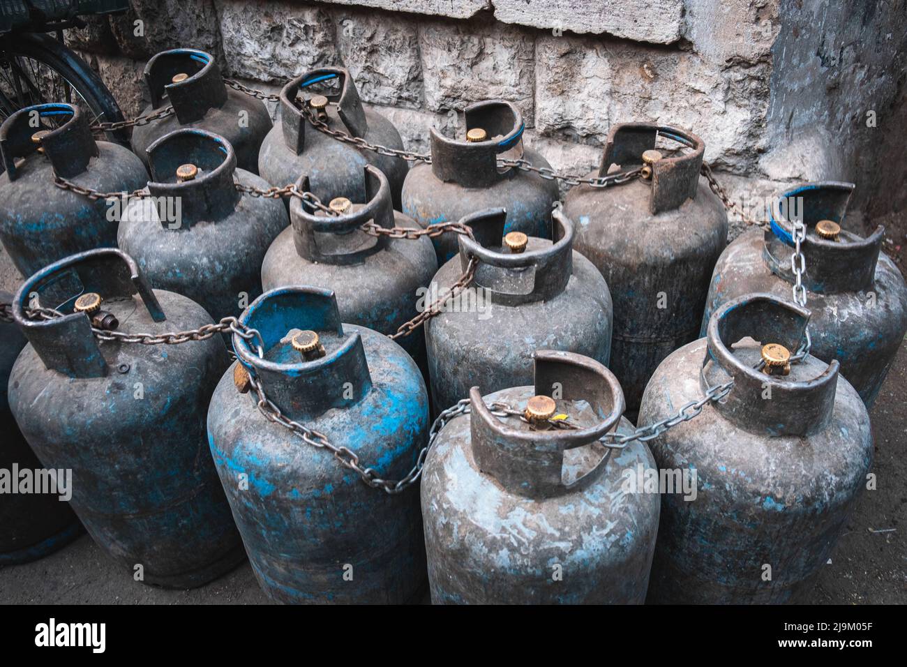 Old, used propane gas bottles secured with chain Stock Photo