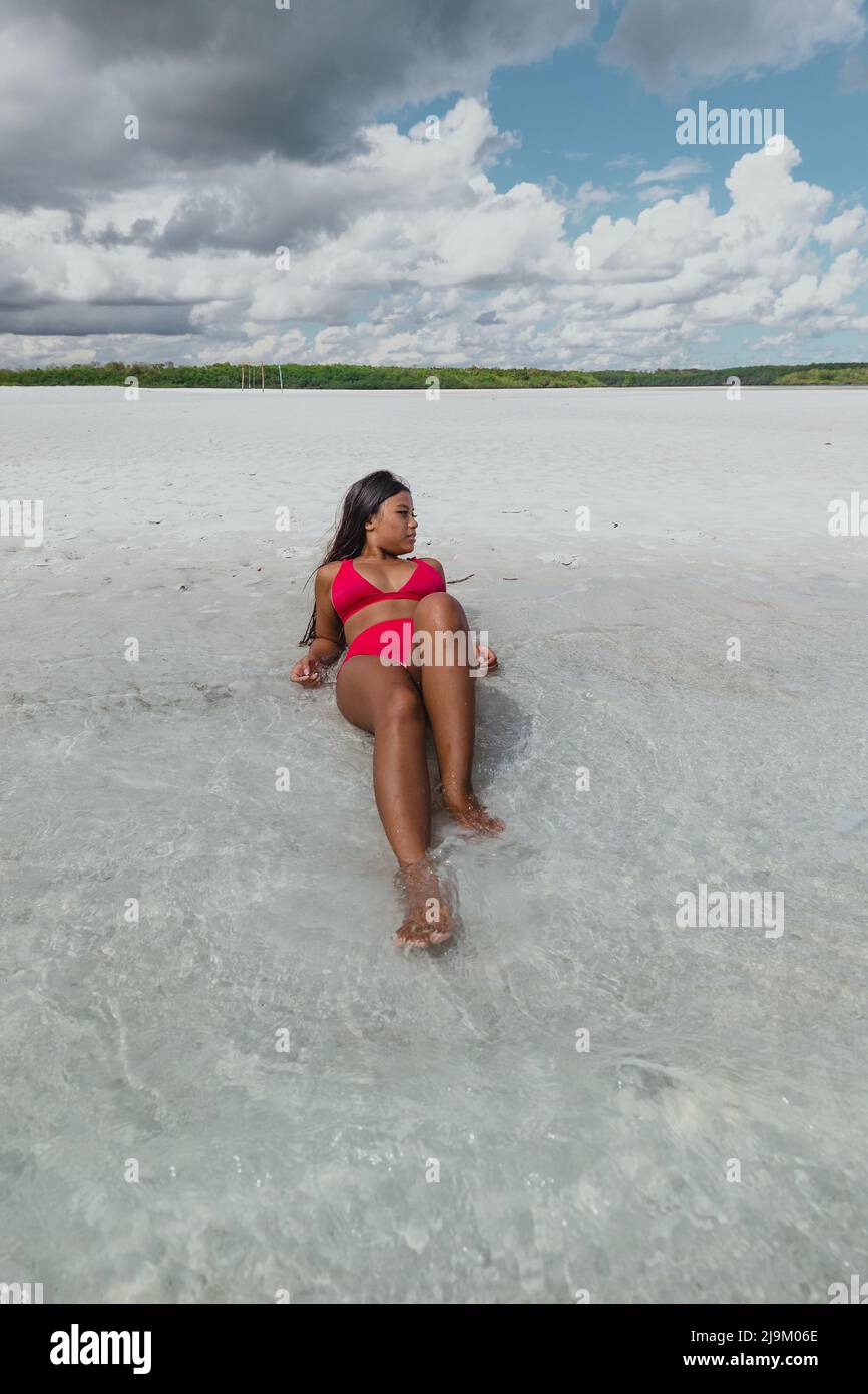 young tan asian model with a red bikini swimsuit laying on Leebong private island with a pristine white sand beach and green mangrove on a sunny day Stock Photo