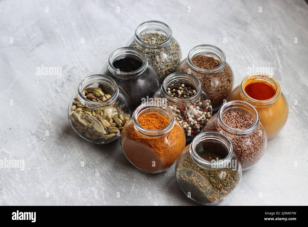 Small glass jars with different spices. Peppercorn, cardamom, turmeric