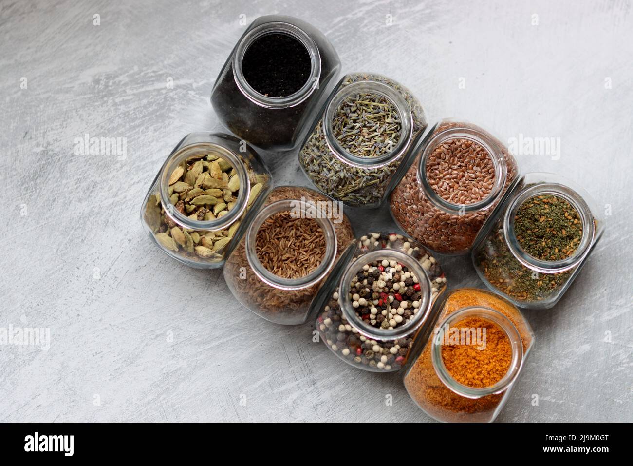 Small glass jars with different spices. Peppercorn, cardamom, turmeric