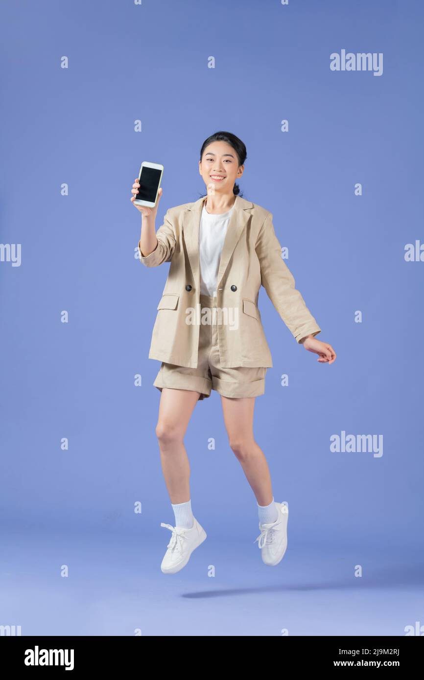 Cheerful girl jumping up and newest smartphone showing empty screen ...