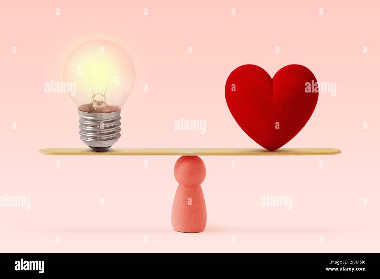 Light bulb and heart on scale on pink background- Concept of woman and balance between heart and brain Stock Photo