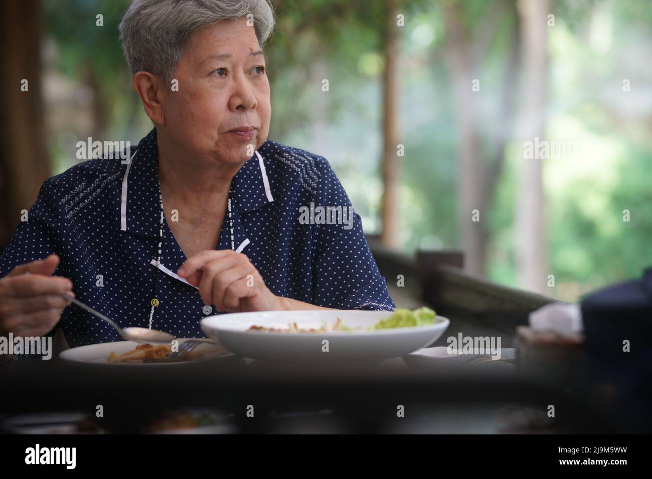 old elderly senior elder woman eating food on terrace. mature retirement lifestyle Stock Photo