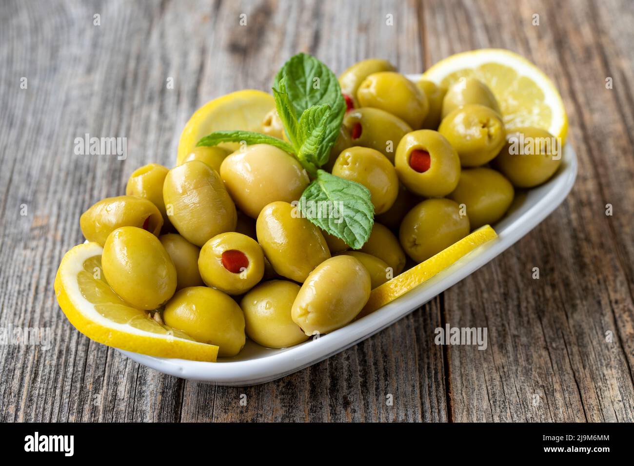 Green olives stuffed with peppers. Natural peppered olives on wood