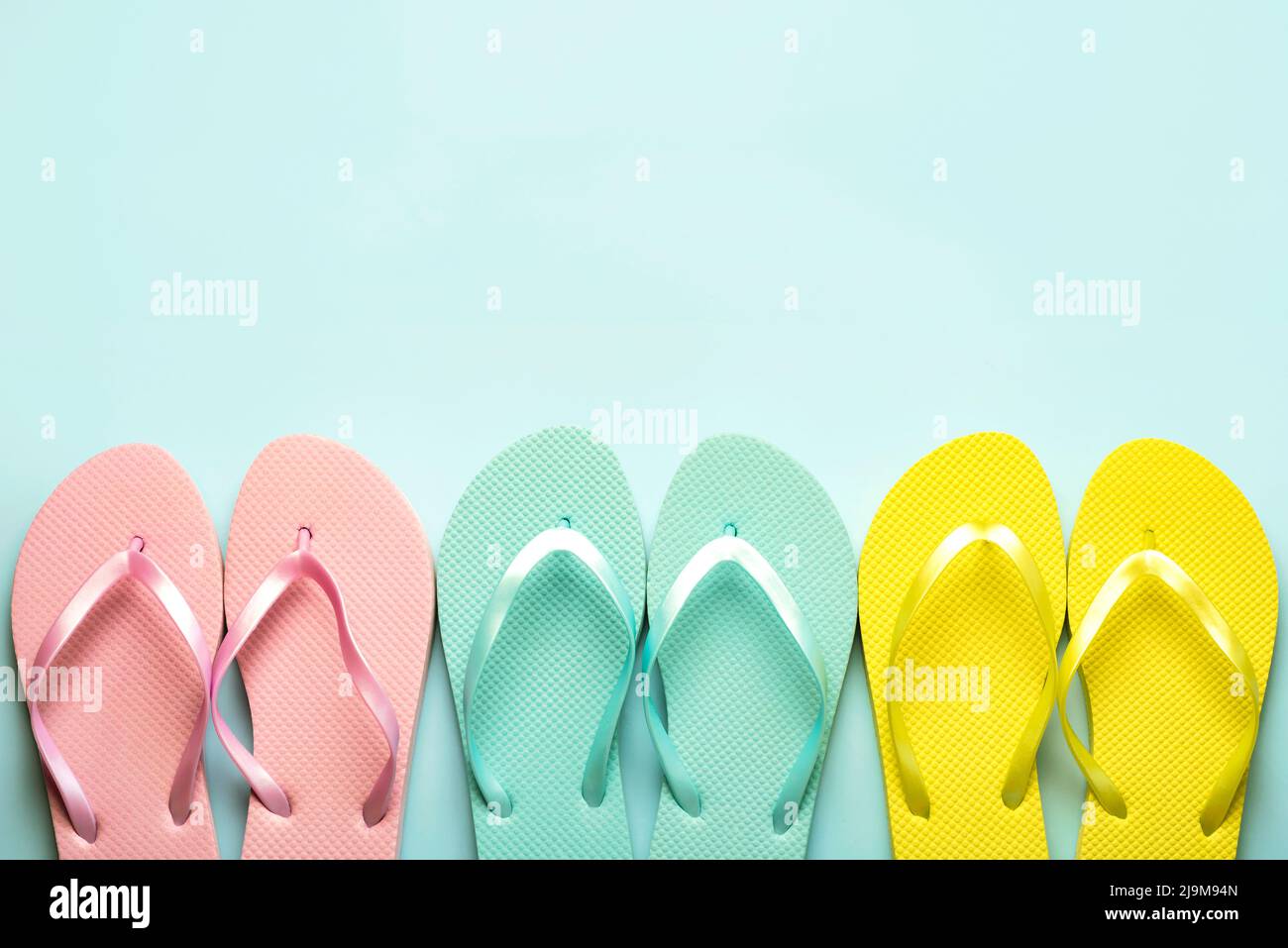 Summer holiday concept.Top view of colored beach flip flops with space for text over blue background Stock Photo