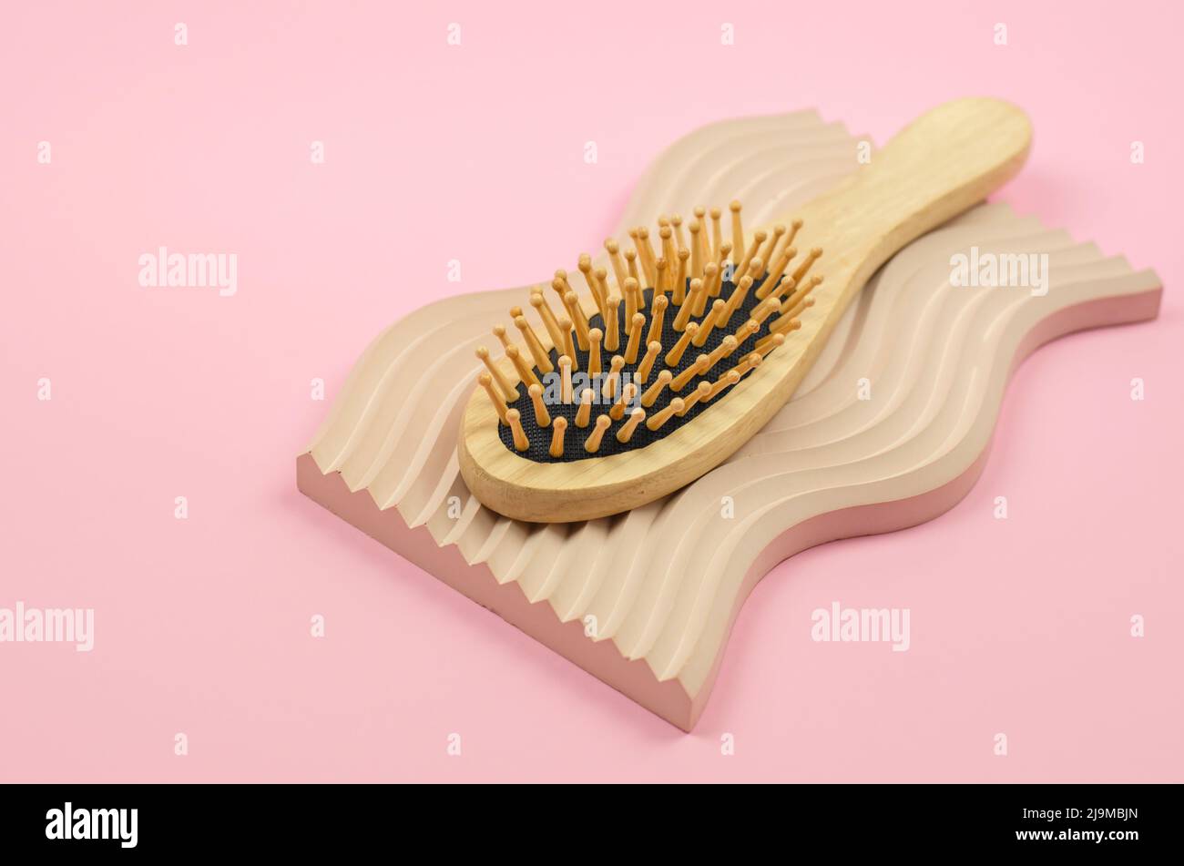 Hairbrush made of natural material. Wooden hairbrush on a beige plaster