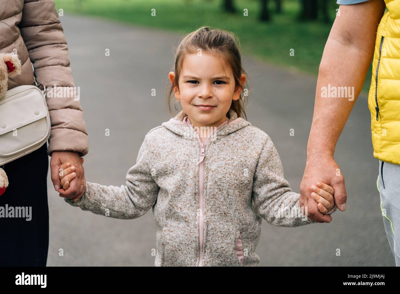 Crop mature grandparents in casual clothes holding hands of adorable