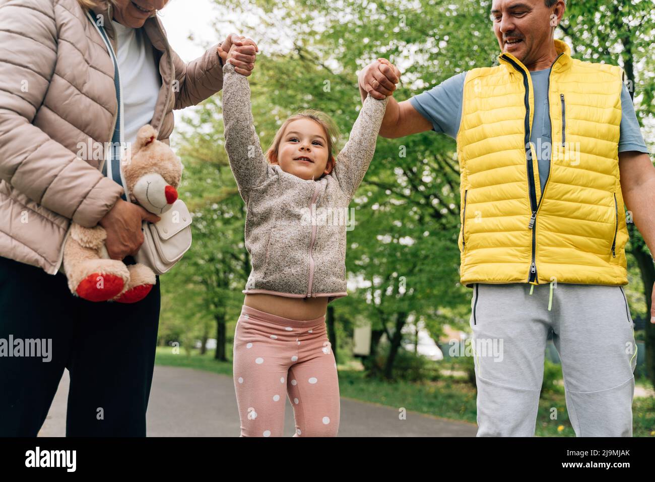 Crop mature grandparents in casual clothes holding hands of adorable