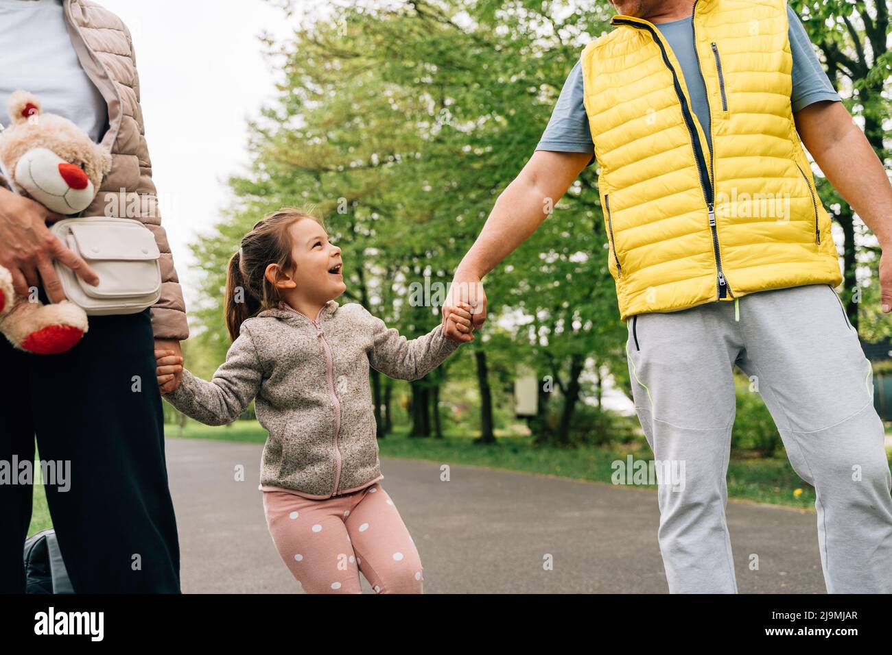 Crop mature grandparents in casual clothes holding hands of adorable