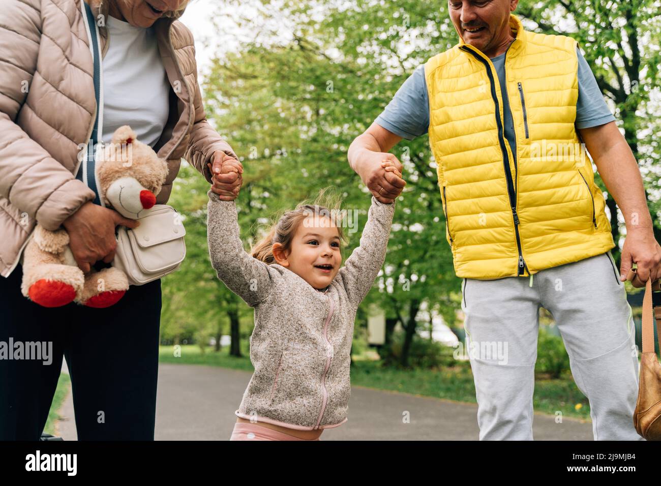 Crop mature grandparents in casual clothes holding hands of adorable