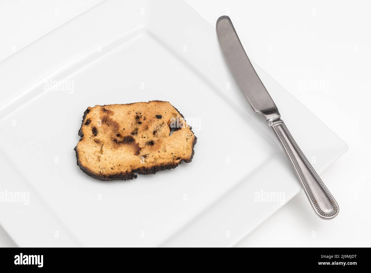 Bread which has been overcooked and burnt to a cinder on one side. For acrylamide and cancer, food unfit to eat, poor kitchen skills, unable to cook. Stock Photo