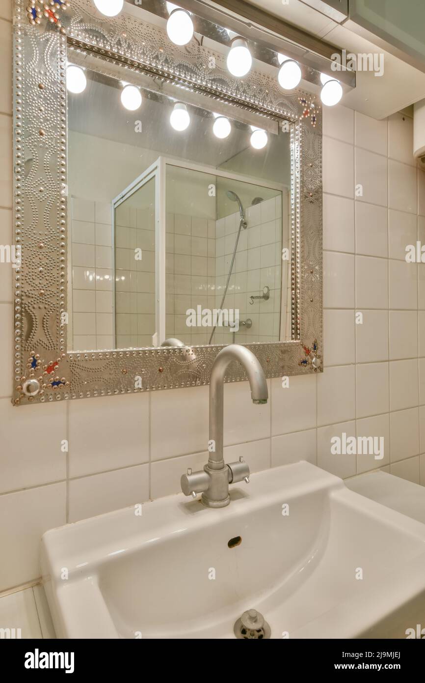 Sink and with mirror placed in tiled wall in bathroom Stock