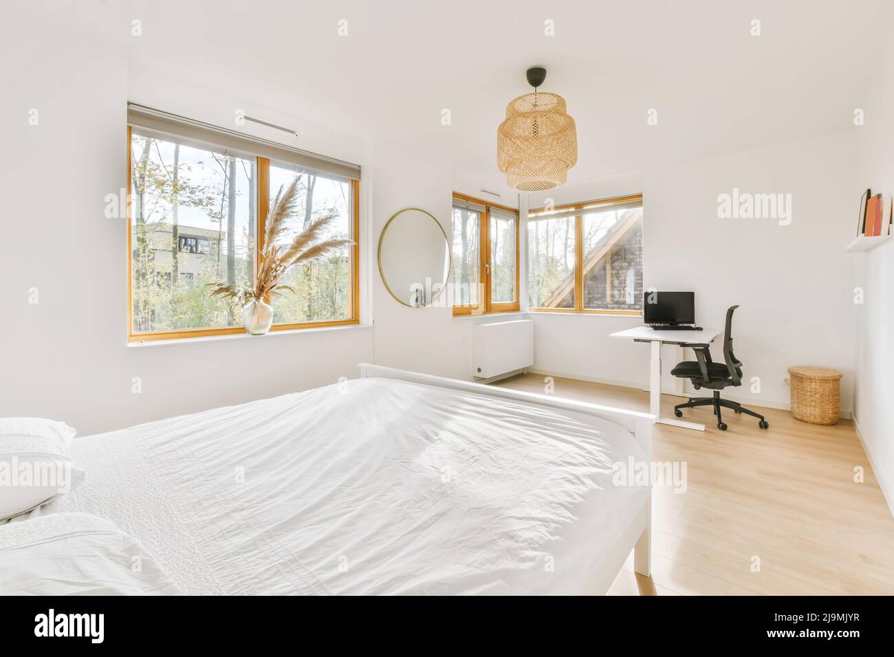 Soft bed with white bedsheet and pillows located near desk with ...