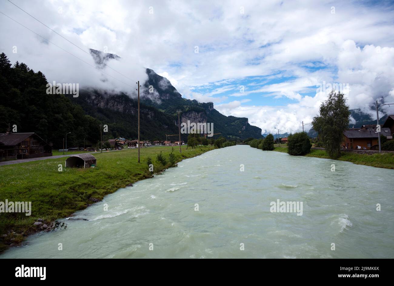 Aare the blue alpine river between narrow rocky cliffs covered with green vegetation and trees, captured at Meiringen , Switzerland. Stock Photo