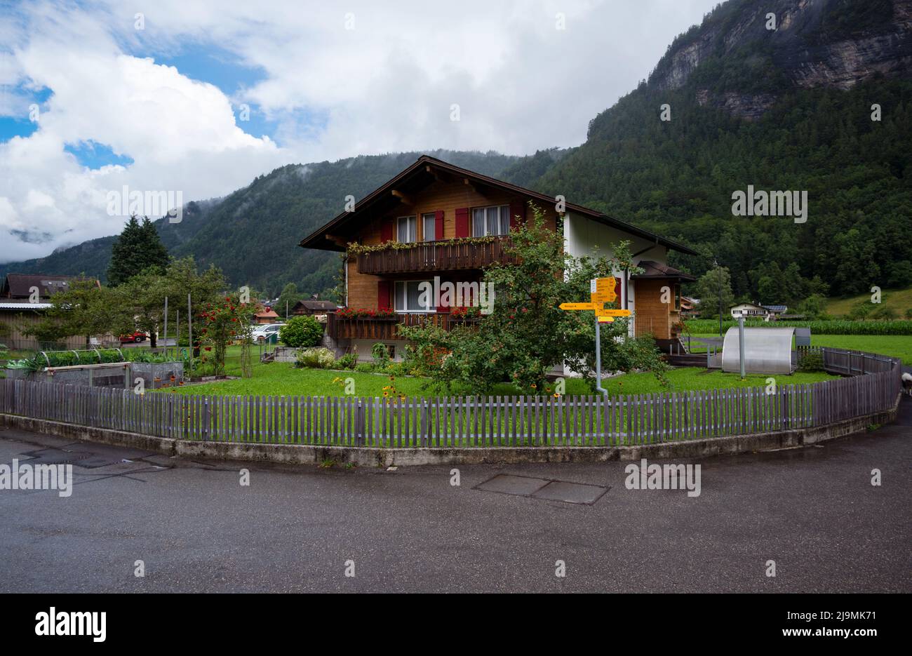 View of a beautiful alpine wooden chalet house with a beautiful and colorful garden and fence captured at Aareschlucht, Switzerland. Stock Photo