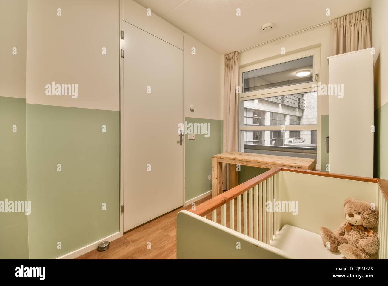 Wooden cot placed near window with curtains in light stylish spacious