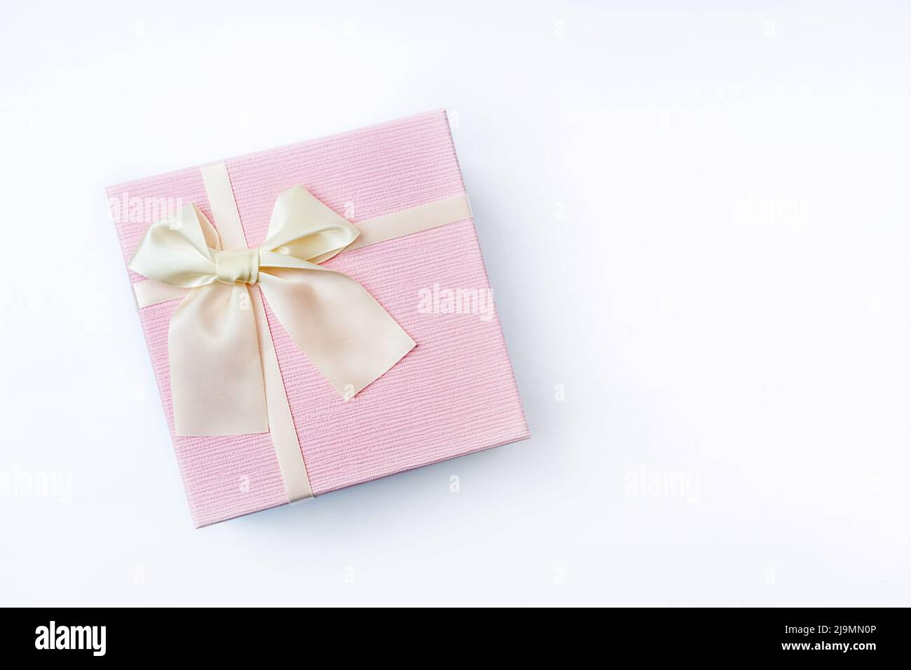 Top view of Delicate pink gift box with satin light ribbon tied in a ...