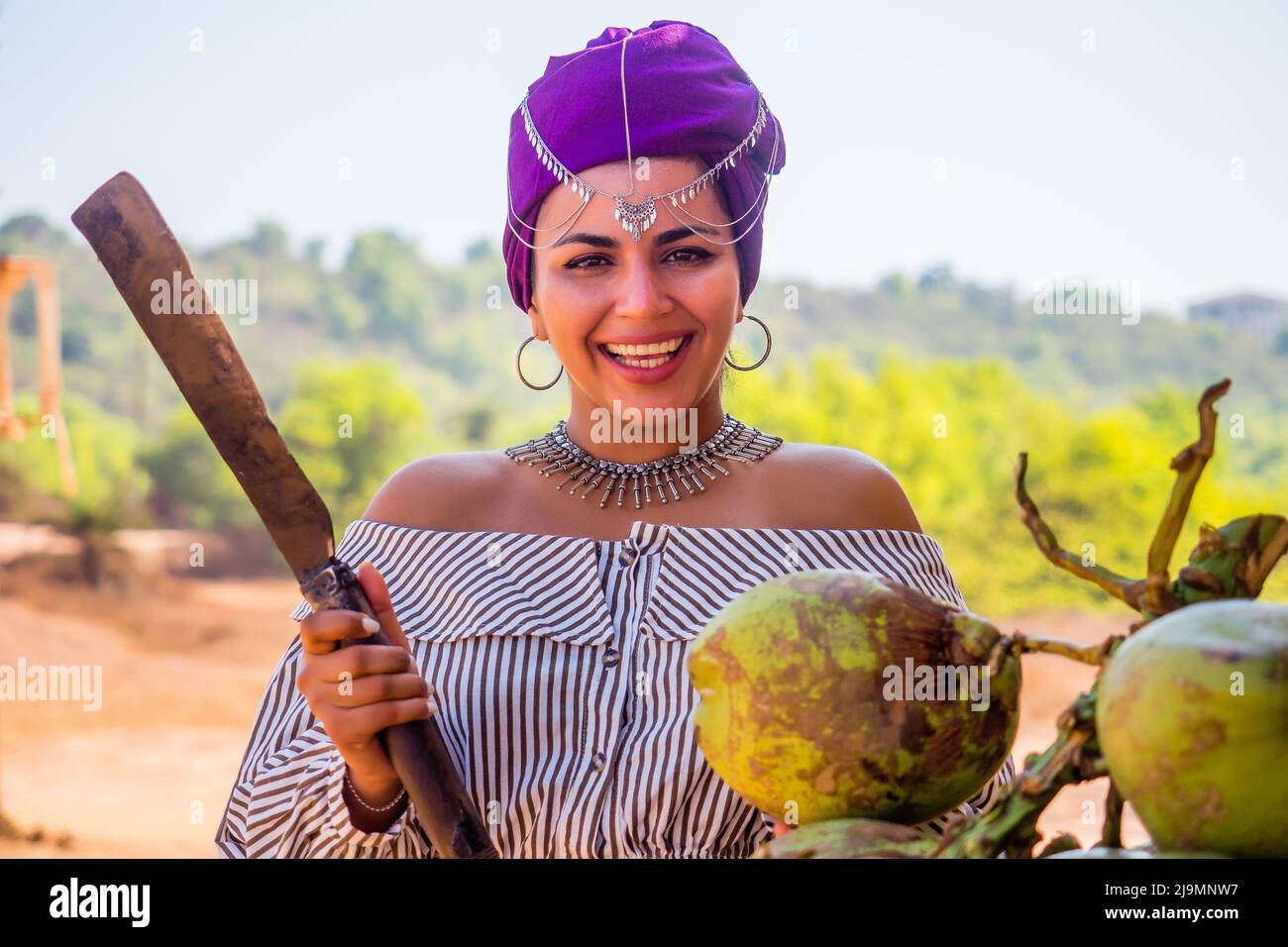 Happy african american woman opening cutting coconut with machete.indian girl open coco nut water in half with a big knife Stock Photo