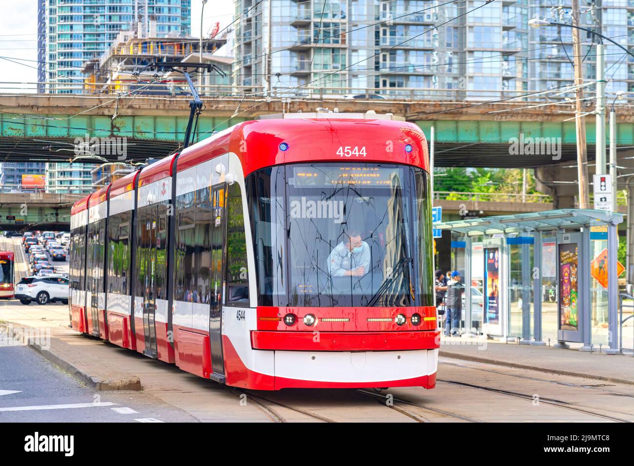 The driver of a TTC streetcar stands from his seat while he waits for the green light at an intersection. The iconic public transportation vehicles ar Stock Photo