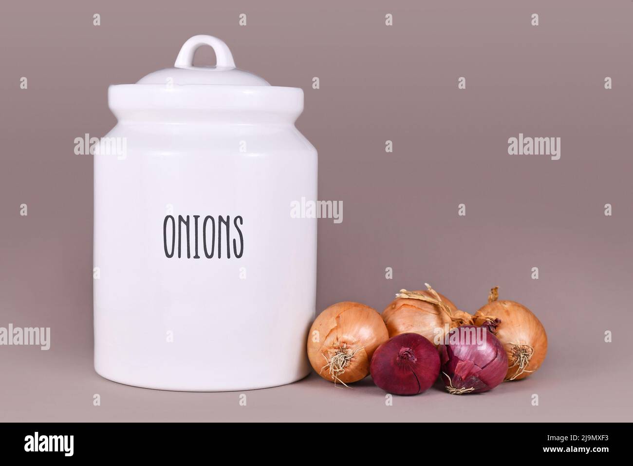 Common yellow and red bulb onions next to storage jar Stock Photo Alamy