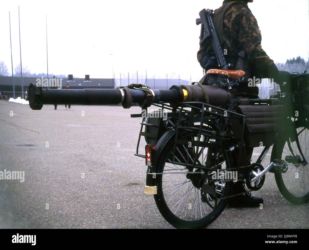 circa 2000, the Swiss army bicycle, MO-93, rear view, showing attached weapon, a bazooka and solider standing. The bicycle was the first major development on the original MO-05, which had introduced in 1905. The Swiss army bicycle or velo militaire has been a part of the national defence of Switzerland since then, as a form of transport, that if needed, enabled the military to move swiftly to defend against any invading forces. It's use dates back to 1891 and although there was talk in 2001 of phrasing them out, a new Swiss Army bike, the MO-12 was introduced in 2012. Stock Photo