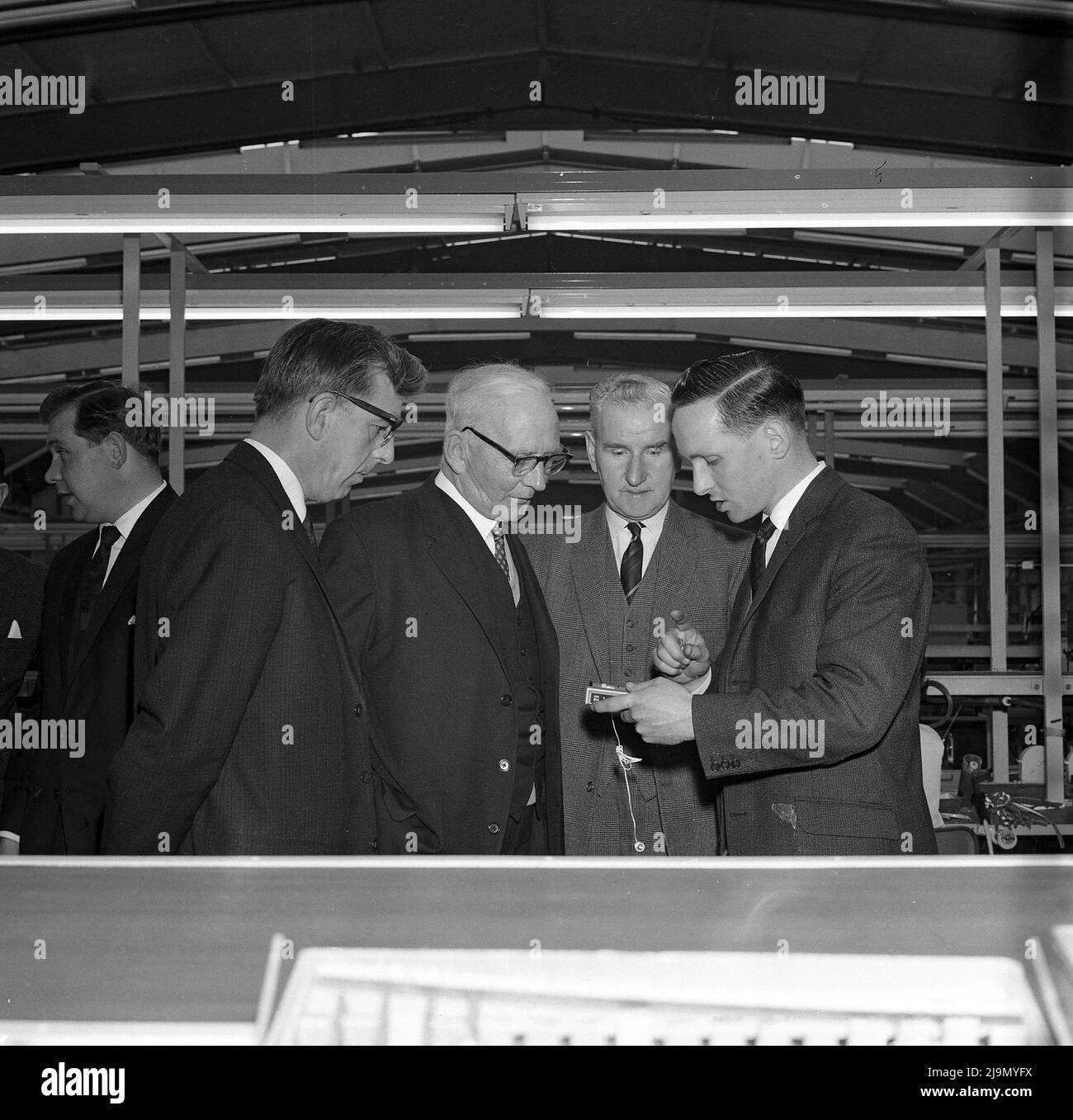 1960s, historical, well-dressed senior management on the factory floor where Phillips transistor radios are being made, Fife, Scotland, UK.  pioneer in the field of radio sets and transistors. Philips was a pioneer in the field of radio sets and transistors, launched its first electronic tubes (radio components) and marketed its first radios in 1927. Stock Photo