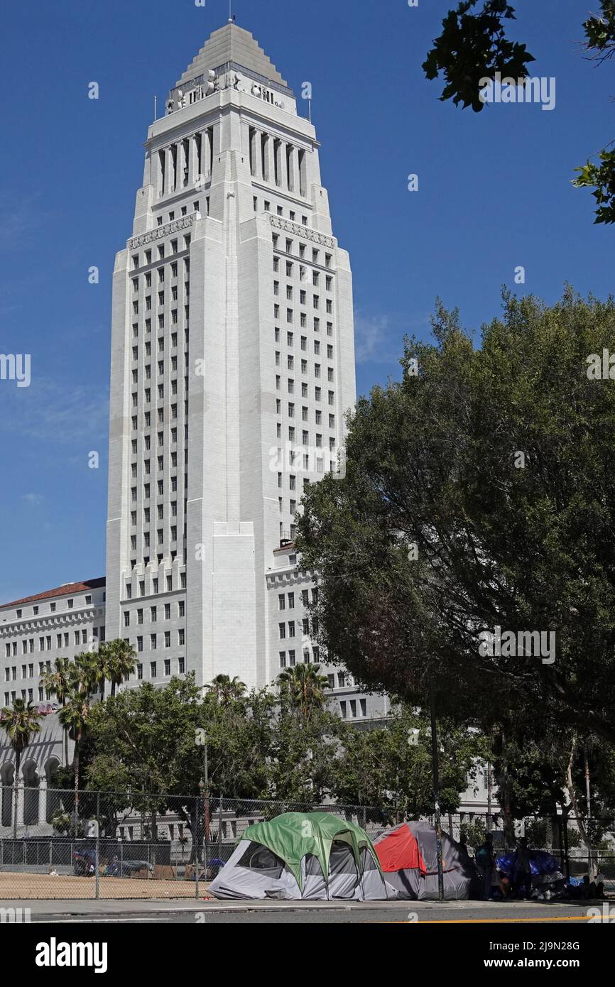 Los Angeles, CA / USA - May 14, 2022: The historic L.A. City Hall tower is shown, with tents of a homeless encampment on the sidewalk below. Stock Photo