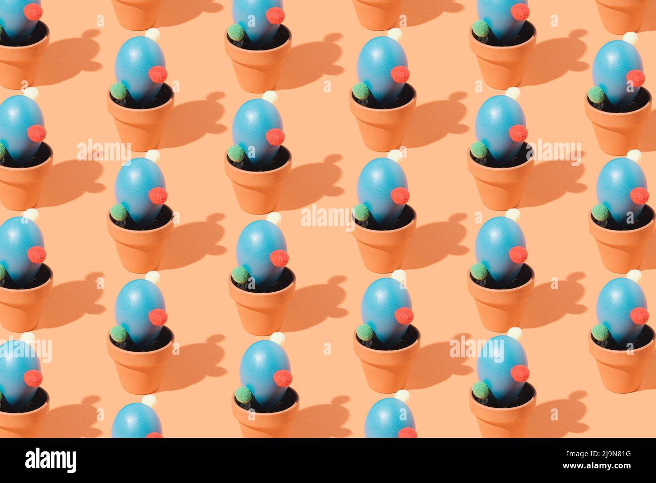 Creative colorful pattern of blue cactus shaped eggs in a flower pots on a brown background. Isometric layout. Easter wallpaper. Stock Photo